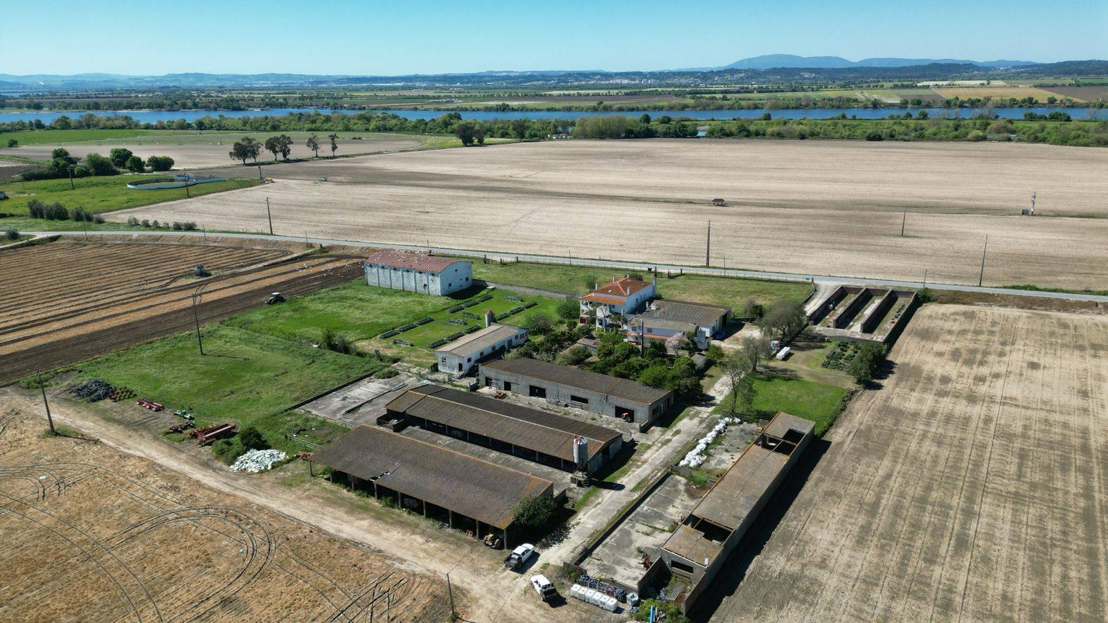 Aerial view of Quinta de S. Nicolau: workshop buildings among open fields, with the Tagus river behind